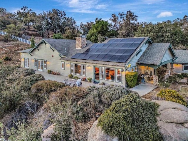 rear view of property featuring a patio and solar panels