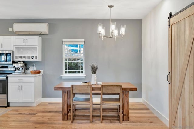 dining room with an inviting chandelier, a barn door, light hardwood / wood-style flooring, and an AC wall unit