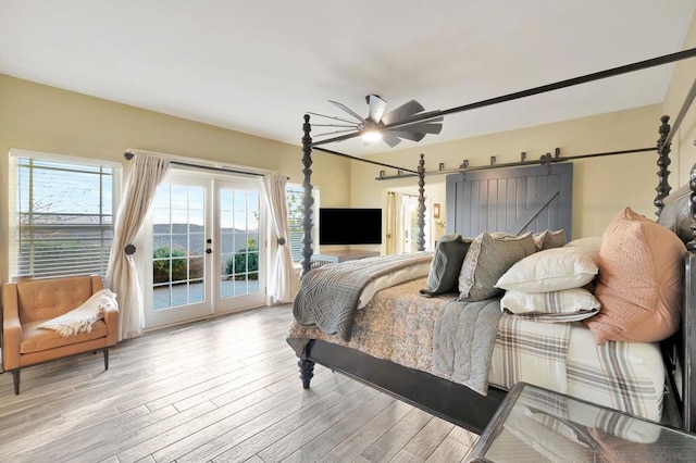 bedroom with french doors, access to exterior, ceiling fan, light hardwood / wood-style flooring, and a barn door