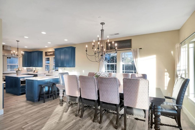 dining area with light wood-type flooring and an inviting chandelier