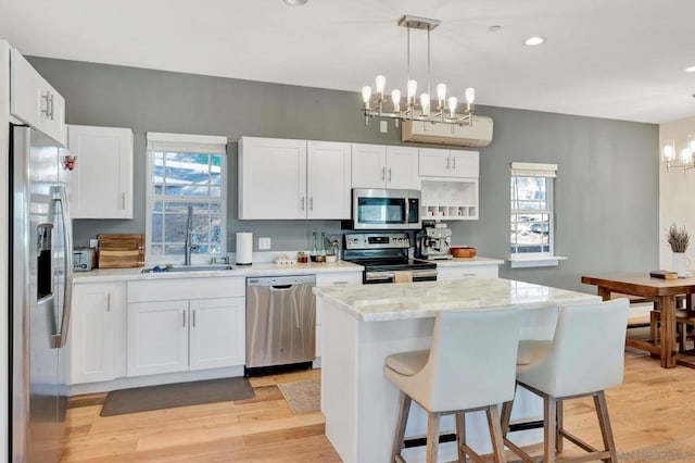 kitchen featuring pendant lighting, white cabinets, appliances with stainless steel finishes, a center island, and a notable chandelier