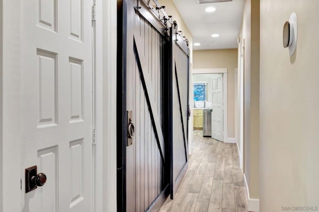 hall featuring light hardwood / wood-style floors and a barn door