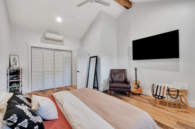 bedroom featuring wood-type flooring, a closet, a wall unit AC, ceiling fan, and lofted ceiling with beams