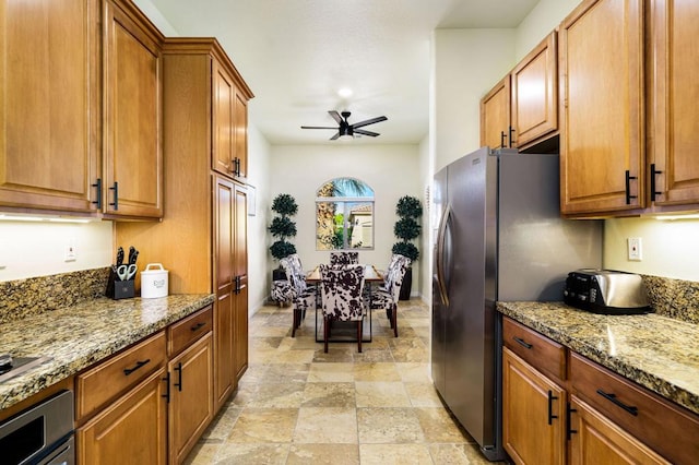 kitchen with wall oven, ceiling fan, stainless steel fridge with ice dispenser, and light stone counters