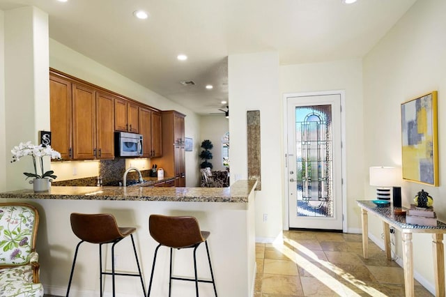 kitchen with dark stone countertops, kitchen peninsula, a breakfast bar, and sink