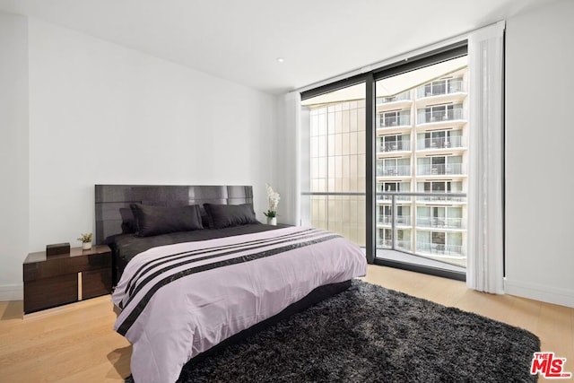 bedroom with floor to ceiling windows and light wood-type flooring