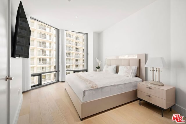 bedroom with floor to ceiling windows and light hardwood / wood-style flooring