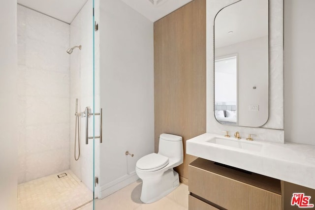 bathroom featuring toilet, vanity, tile patterned floors, and a tile shower