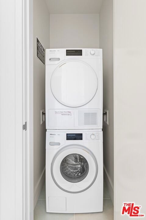 washroom with stacked washer and dryer and tile patterned flooring