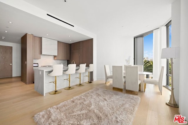 kitchen with a kitchen breakfast bar, light hardwood / wood-style flooring, a center island, and expansive windows