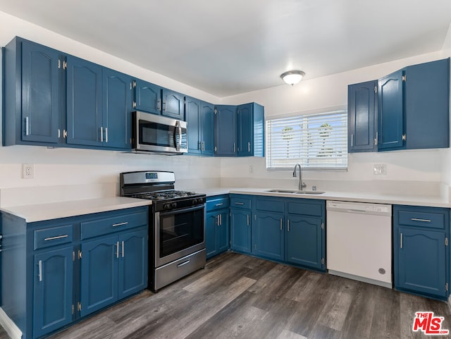 kitchen with appliances with stainless steel finishes, blue cabinets, dark hardwood / wood-style floors, and sink