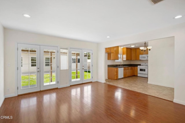 kitchen featuring white appliances, decorative light fixtures, french doors, sink, and plenty of natural light