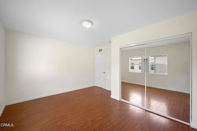 unfurnished bedroom with dark wood-type flooring and a closet