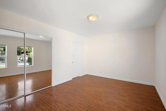 unfurnished bedroom featuring a closet and dark wood-type flooring