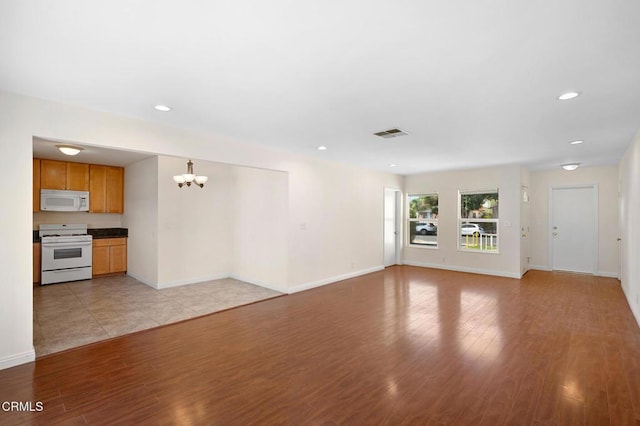 unfurnished living room with light wood-type flooring and a chandelier