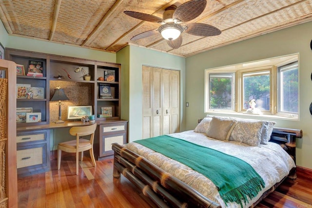 bedroom with hardwood / wood-style flooring, built in desk, ceiling fan, and a closet