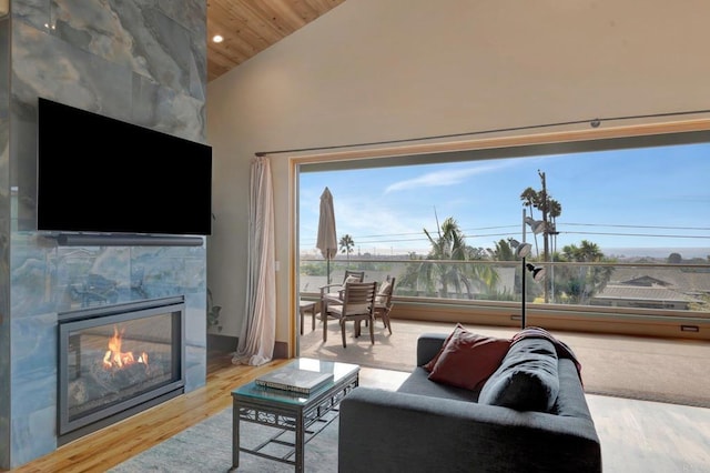 living room featuring a tile fireplace, high vaulted ceiling, and light wood-type flooring