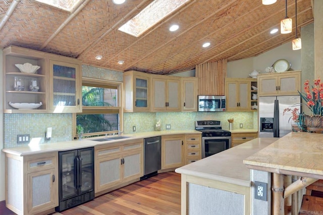 kitchen with wine cooler, a breakfast bar area, appliances with stainless steel finishes, pendant lighting, and light hardwood / wood-style floors