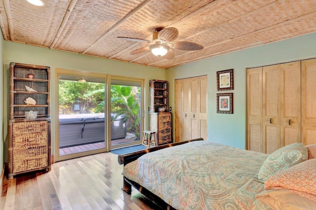 bedroom featuring hardwood / wood-style floors, two closets, access to exterior, and ceiling fan