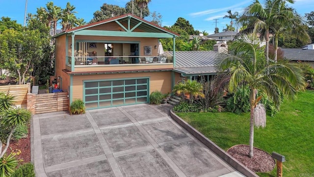 view of front of house with a balcony, a garage, and a front yard