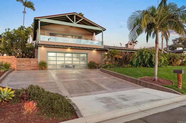 view of front of home with a garage, a front yard, and a balcony