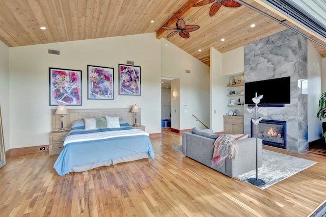 bedroom with high vaulted ceiling, a tiled fireplace, wood ceiling, light hardwood / wood-style floors, and beam ceiling