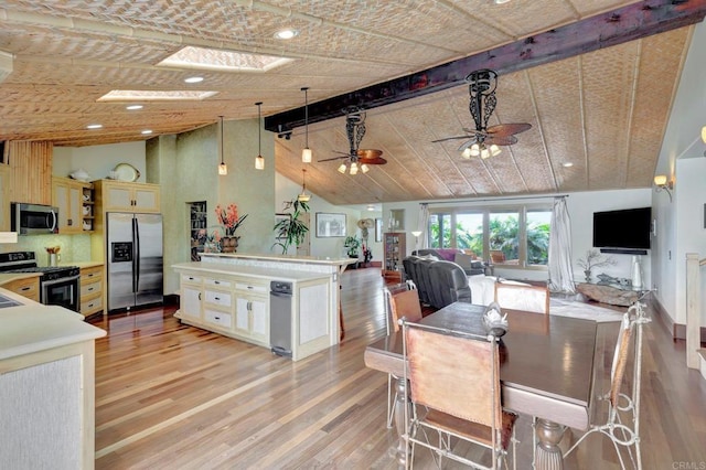 dining space with high vaulted ceiling, a skylight, beamed ceiling, ceiling fan, and light hardwood / wood-style flooring