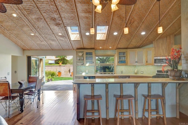 kitchen with pendant lighting, sink, a kitchen breakfast bar, tasteful backsplash, and wood-type flooring