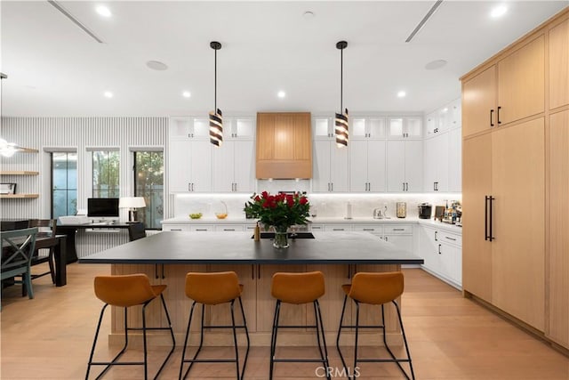 kitchen featuring white cabinetry, hanging light fixtures, a center island, and premium range hood