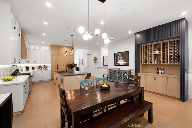 dining room featuring sink, light hardwood / wood-style flooring, and a barn door