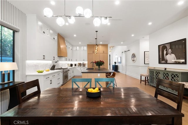 dining room featuring sink, light hardwood / wood-style flooring, and a barn door