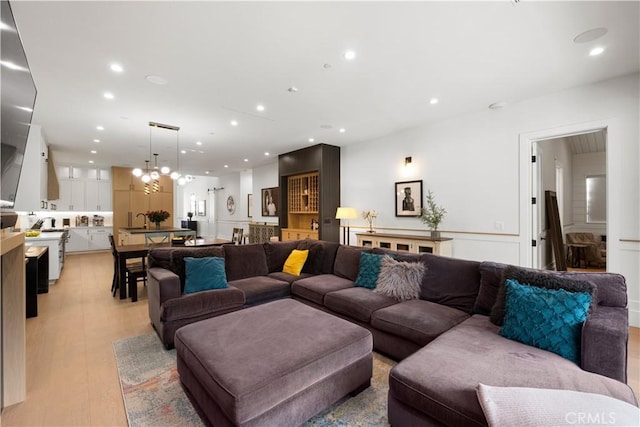 living room with light hardwood / wood-style floors, sink, and a notable chandelier