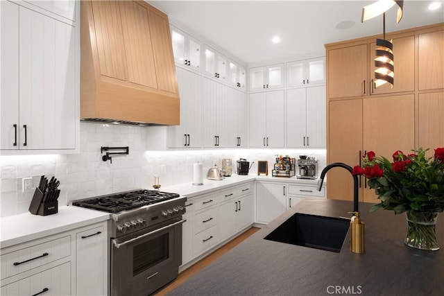 kitchen featuring white cabinetry, sink, stainless steel range, and custom range hood