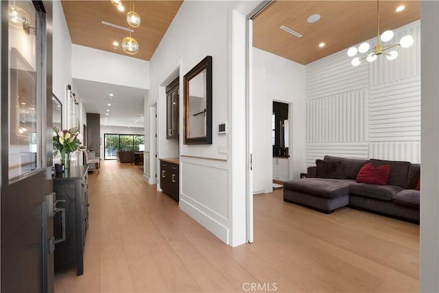 hallway with an inviting chandelier, wood ceiling, and light hardwood / wood-style flooring