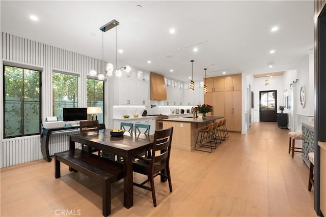 dining space featuring sink, a notable chandelier, and light hardwood / wood-style floors