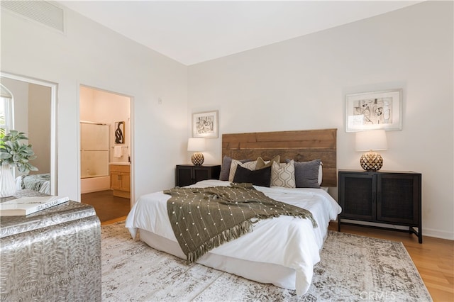 bedroom with connected bathroom and light hardwood / wood-style flooring