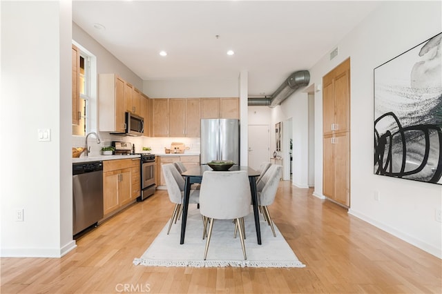 kitchen featuring light hardwood / wood-style flooring, light brown cabinetry, and appliances with stainless steel finishes