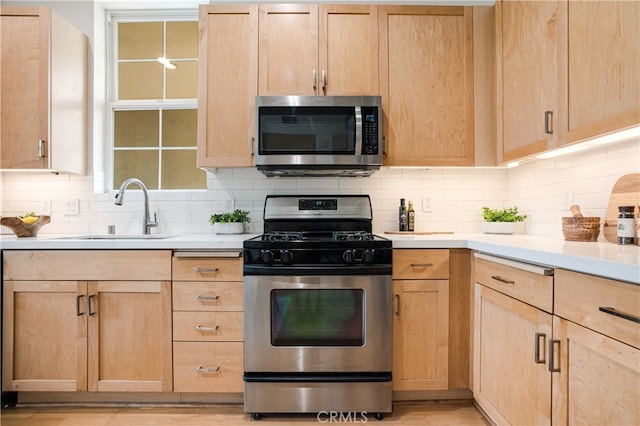 kitchen featuring sink, backsplash, light brown cabinetry, and appliances with stainless steel finishes