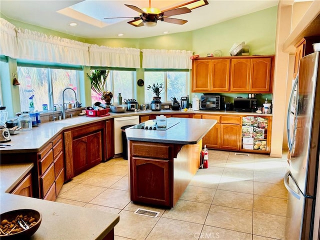 kitchen with dishwasher, a kitchen island, sink, stainless steel fridge, and light tile patterned flooring