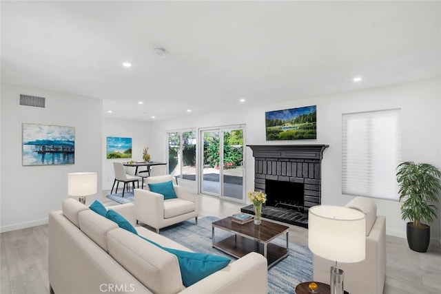 living room with a brick fireplace and light hardwood / wood-style flooring