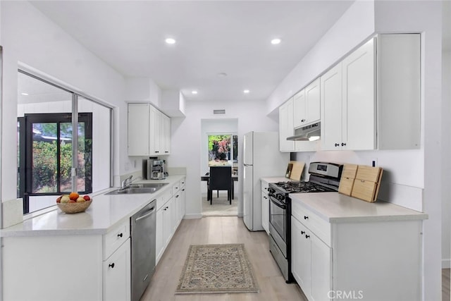 kitchen with white cabinets, sink, stainless steel appliances, and light hardwood / wood-style flooring