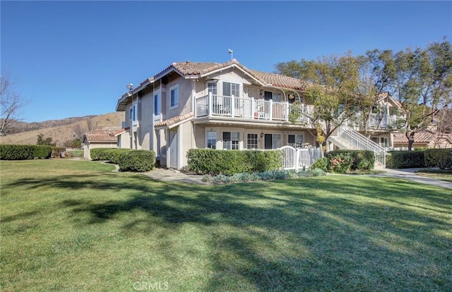 view of front of home featuring a balcony and a front lawn