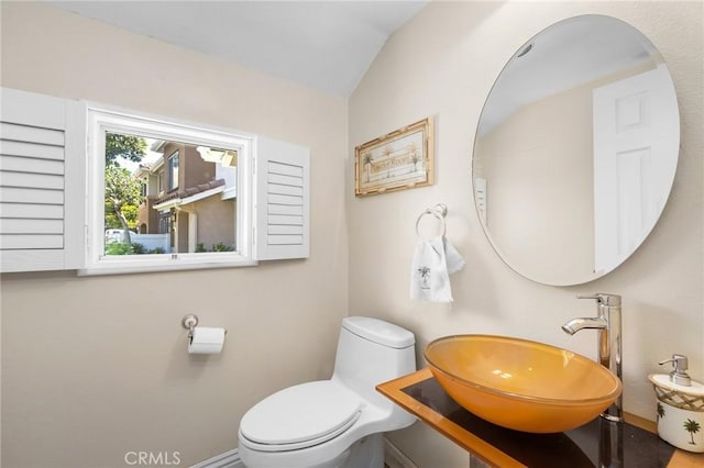 bathroom featuring sink, toilet, and vaulted ceiling