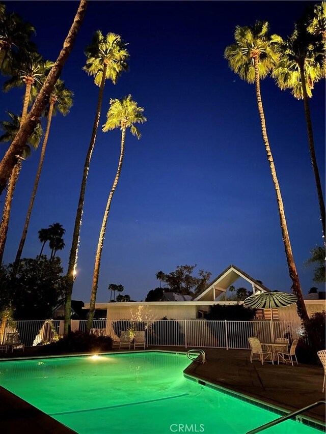 pool at night featuring a patio area