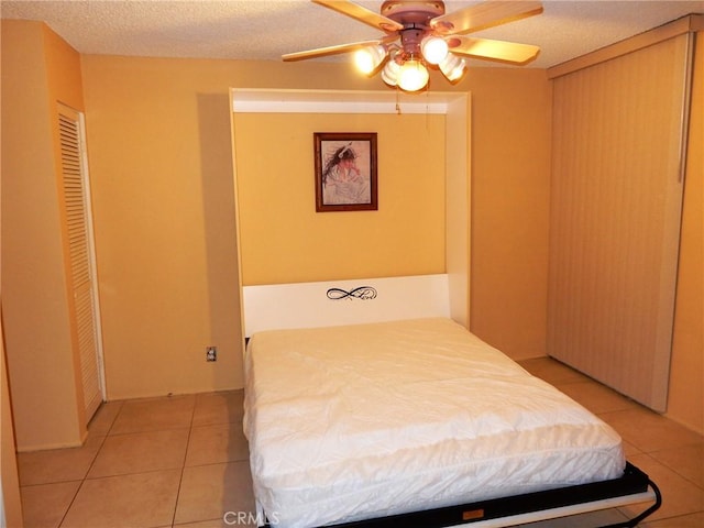 tiled bedroom with ceiling fan and a textured ceiling