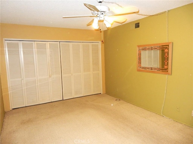 unfurnished bedroom featuring carpet, ceiling fan, and a closet