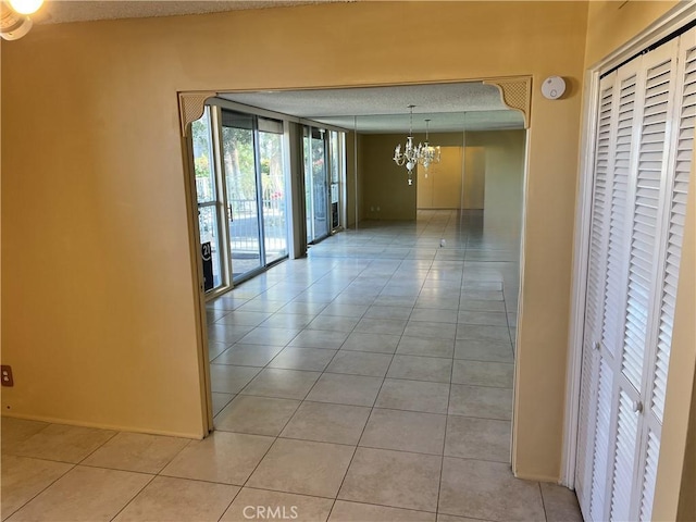 hallway featuring an inviting chandelier and light tile patterned flooring