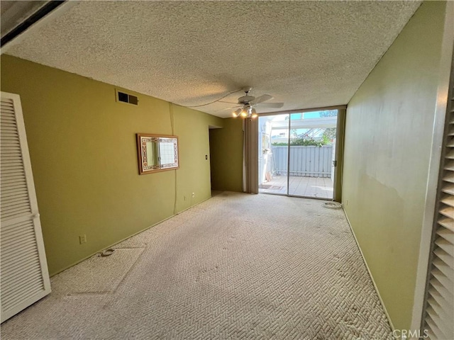 carpeted empty room with ceiling fan and a textured ceiling