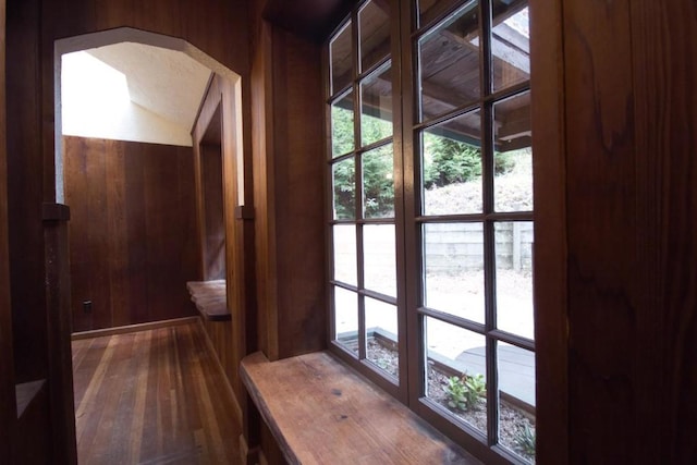 doorway to outside with dark hardwood / wood-style flooring and wood walls