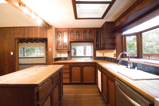 kitchen featuring dishwasher, dark hardwood / wood-style floors, sink, wooden walls, and wood counters